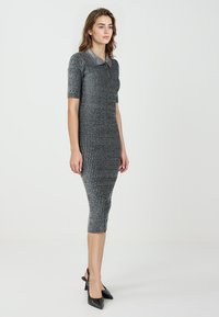 Robe en tricot gris foncé à manches courtes et col. Design ajusté, longueur genou, présentant un motif texturé avec des fils métalliques.