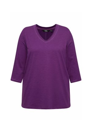 T-shirt viola con scollatura a V e maniche a tre quarti realizzato in tessuto morbido e texturizzato, con cuciture sottili lungo il colletto e l'orlo delle maniche.