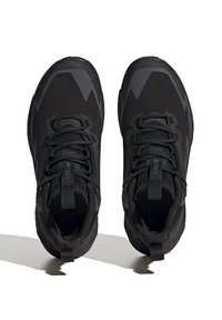 Schwarze Sportschuhe mit einer strukturierten Mesh-Oberfläche, Schnürverschluss und verstärktem Absatz, ausgestattet mit einer robusten Gummisohle und markanten, kantigen Akzenten.