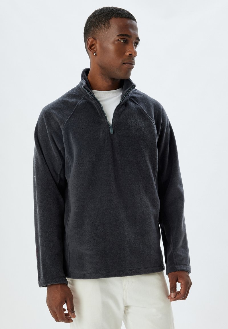 Fleece-pullover i mörkgrå, med hög krage, kvartslång dragkedja framtill och raglanärmar. Mjuk textur och avslappnad passform.