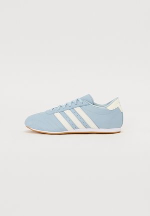 Ljusblå sportskor med vita ränder, tillverkade av slätt läder, med ett perforerat mönster, rund tå och gummisula.