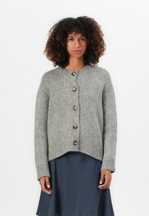 Gray knitted cardigan with a round neckline, five large buttons down the front, and ribbed texture. Worn over a dark, flowy dress.