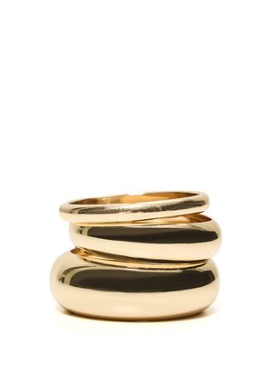 Tri vrstvy lesklých zlatých prsteňov rôznej hrúbky na bielom pozadí.