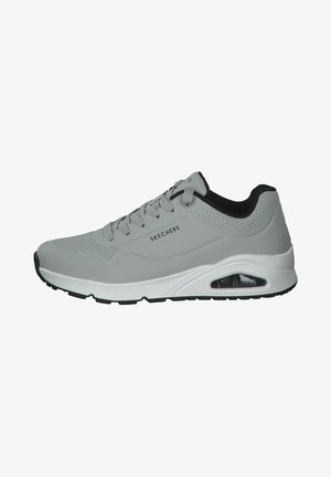 Shoe desportivo cinza com parte superior sintética, detalhes perfurados, entressola branca e sola preta. Cadarços e nome da marca visíveis na lateral.
