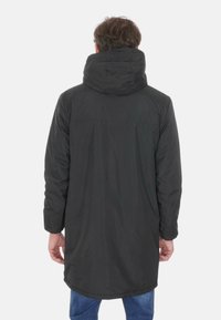 Cappotto lungo nero con cappuccio, realizzato in tessuto morbido. Presenta un taglio dritto e un sottile logo del marchio sulla parte posteriore.