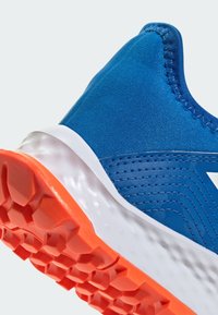 Niebieski but sportowy z teksturowaną cholewką, białą podeszwą środkową i pomarańczową gumową podeszwą zewnętrzną. Charakteryzuje się ukośnymi liniami i akcentami szwów.