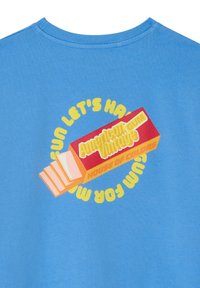 T-shirt en coton bleu avec un imprimé graphique d'un paquet de chewing-gum en rouge et jaune avec du texte, design circulaire autour du logo central.