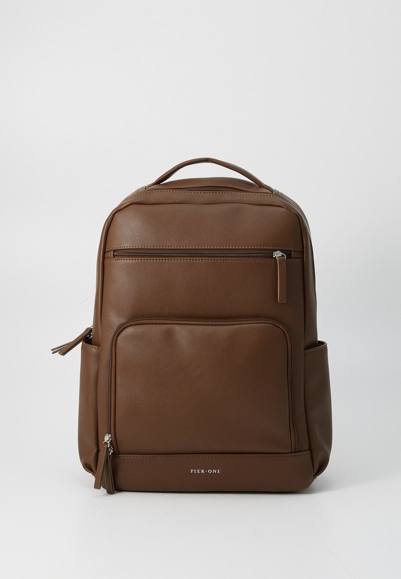 Brown leather backpack with a smooth texture, featuring a top handle, front zip pocket, and side pocket. Brand logo visible on the front.