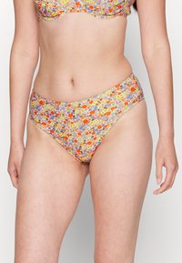 O fundo de bikini com padrão floral apresenta uma base amarelo-clara com flores multicoloridas, cobertura moderada e textura de tecido suave.