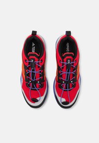 Rote und schwarze Sportschuhe mit Mesh-Obermaterial, orangefarbenen Akzenten und lila Schnürsenkeln. Mit einer Gummisohle und einem Zugband für einfaches Anziehen.