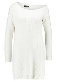 Robe pull blanche en tricot avec un col large, des manches longues et une texture côtelée. Caractérisée par une coupe décontractée et des fentes latérales à l'ourlet.
