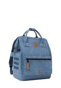 Zaino impermeabile blu con doppio manico, spallacci regolabili, tasca anteriore con zip e patch rotondo con logo. Texture liscia e design elegante.