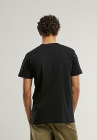 Svart bomulls t-skjorte med korte ermer og rund hals. Har en jevn tekstur og en avslappet passform. Ingen synlige mønstre eller detaljer.