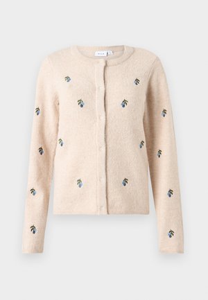 Bēša kardigāna ar garām piedurknēm, apaļu kakla izgriezumu un pogu priekšpusi. Rotāta ar zilas un zaļas krāsas ziedu izšuvumiem. Mīksta tekstūra.