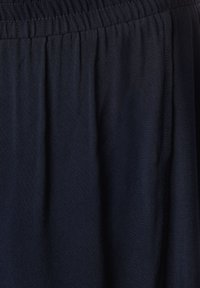 Námořnická modrá sukně s elastickým pasem, vyrobená z měkké a splývavé látky, se spoustou skladů pro větší pohyb a texturu.