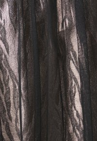 Tessuto nero trasparente con strisce in bronzo metallico, caratterizzato da una finitura testurizzata e un design fluido e plissettato.