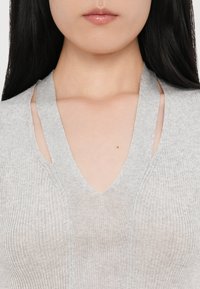 Top grigio a coste senza maniche con scollatura a V profonda, caratterizzato da dettagli a taglio sulle spalle e una texture morbida.