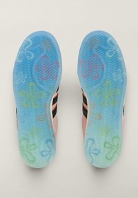Niebieskie gumowe podeszwy butów z wzorem jodełkowym. Zawierają kolorowe, fantazyjne kwiatowe i abstrakcyjne wzory na całej powierzchni.