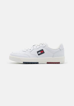 Białe sneakersy z gładką skórzaną cholewką, perforowanym noskiem, kontrastującymi czerwonymi i niebieskimi akcentami na podeszwie oraz naszywką z logo po boku.