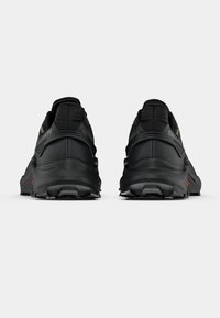 Pár čiernych športových topánok s robustnými podrážkami, zobrazených zozadu na jednoduchom bielom pozadí.