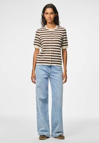 Bruin en crème gestreepte kortmouw cardigan met knopen, gecombineerd met lichtblauwe wijdbeenjeans en bruine schoenen.