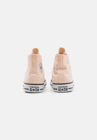 Rosa lerrets høye sneakers med sorte og hvite gummisåler, som har et sirkulært logo på ankelen og en sydd sømdetalj.