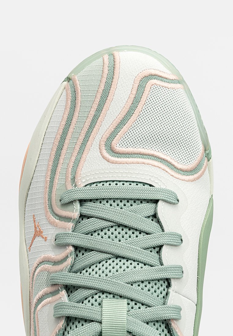 Sneaker con una toma superiore in mesh verde e bianco, caratterizzata da motivi ondulati testurizzati, dettagli rosa e suola in gomma. Include lacci verdi e logo.