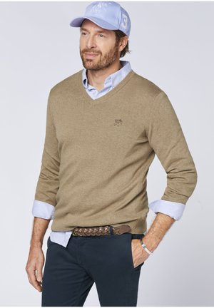 Beige knitted V-neck sweater over a light blue collared shirt, paired with navy pants and a braided brown belt. Light blue cap with logo.