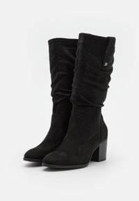 Bottes noires en daim montantes avec un design décontracté, une pointe fine et un talon bloc. Présente un petit accent métallique sur le côté.