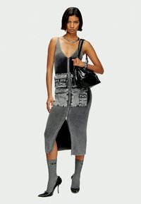 Μαύρο και γκρι ριγέ φόρεμα με φερμουάρ και αξεσουάρ από τζιν φούστα, με άνοιγμα στο πλάι, συνδυασμένο με γκρι κάλτσες μέχρι το γόνατο και μαύρες μυτερές γόβες. Μαύρη τσάντα.