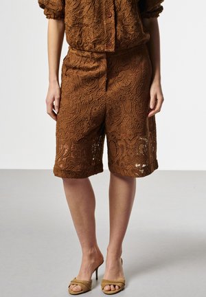 Bruine, ingewikkelde kanten knielange shorts gecombineerd met een bijpassend topje, gedragen met beige slip-on sandalen met hak.