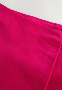 Fuchsia ribbed fabric with a soft texture, featuring a smooth finish and layered folds, highlighting its vivid color and pattern.