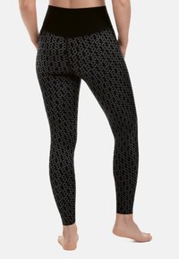 Leggings neri con un motivo testurizzato e disegni intrecciati, vita alta e fitting aderente. Materiale morbido e taglio lungo.