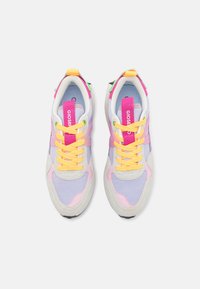 Baskets de sport colorées présentant un mélange de matériaux en violet pastel, rose et beige, avec des lacets et des accents jaunes.