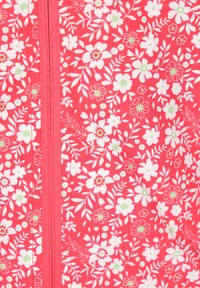 Tessuto rosso con motivo floreale, caratterizzato da fiori bianchi e verdi. Include una cerniera centrale ed è liscio al tatto.