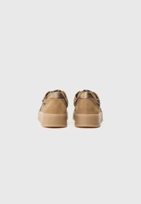 Brown suede sneakers with a smooth metallic accent at the heel, featuring a textured rubber sole and a low-top design.