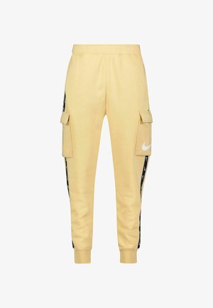 Gele joggingbroek met zijzakken, zwarte zijstrepen en wit Nike-logo. Gemaakt van zacht katoenen materiaal met geribbelde boorden.