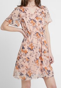 Pfirsichfarbendes Kleid mit Blumenmuster, das orangefarbene und dunkelviolette Details aufweist, kurze Ärmel, V-Ausschnitt, elastischen Taillenbund und durchscheinender Textur hat.