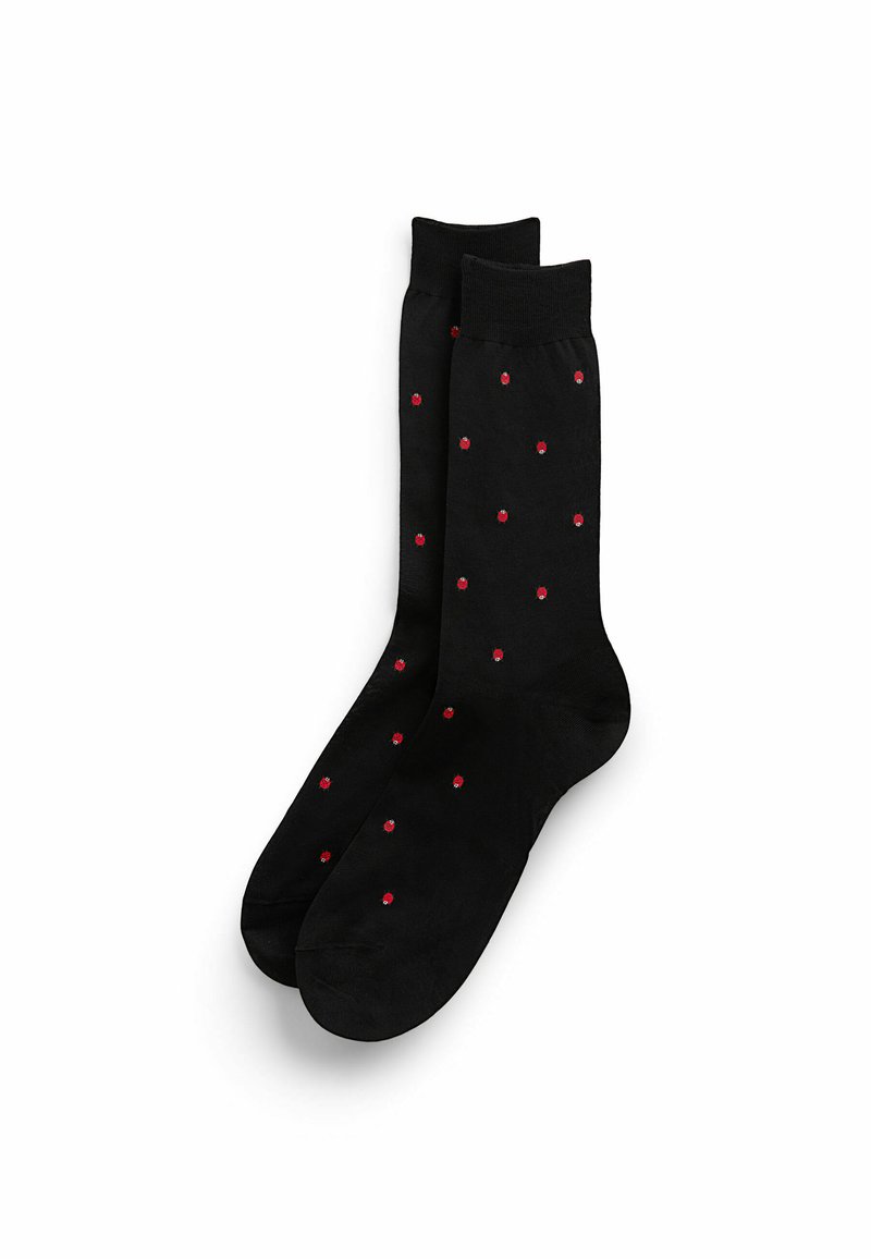 Calzini neri con una texture liscia, caratterizzati da motivi a pois rossi distribuiti uniformemente sulla superficie. Design classico con un bordo morbido.