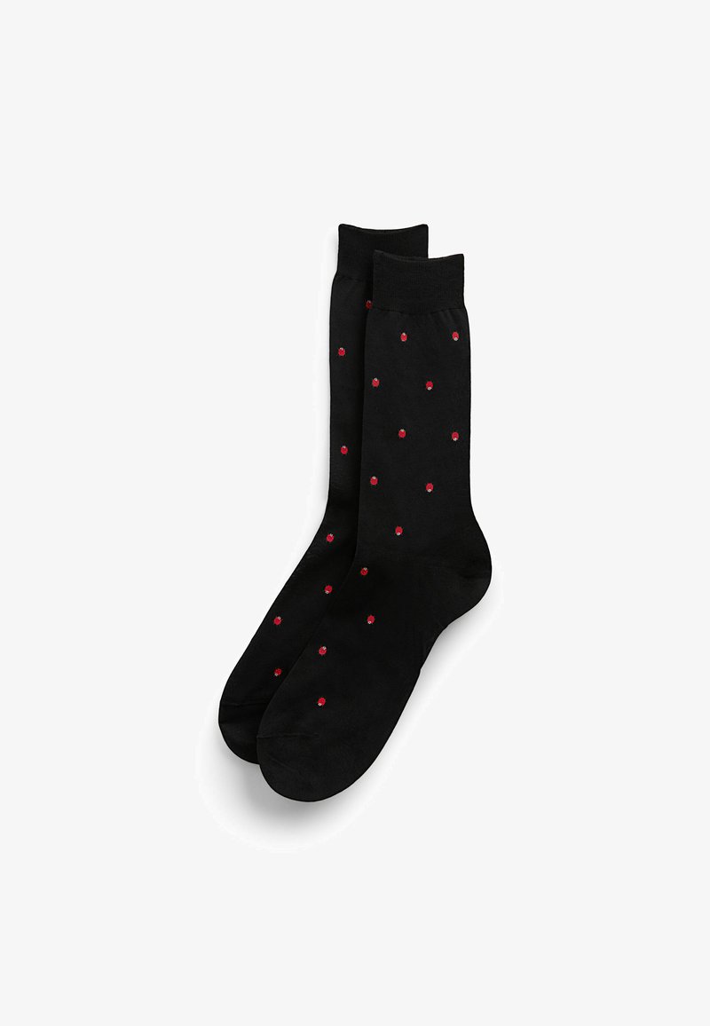 Calcetines negros con una textura suave, decorados con patrones de puntos rojos espaciados uniformemente por toda la superficie. Diseño clásico con un puño suave.