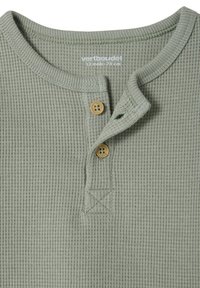 Green ribbed long-sleeve shirt with a henley collar, featuring two wooden buttons and x-stitch detailing at the neckline.