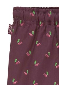 Burgunderfarvet stof med små kirsebær- og bladtryk; har en elastisk talje og en blød tekstur. Brandlabel synligt på siden.