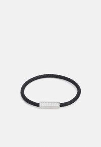 Bracciale di pelle nera intrecciata con una fibbia in argento texturizzato con logo inciso. Forma circolare con finitura liscia.
