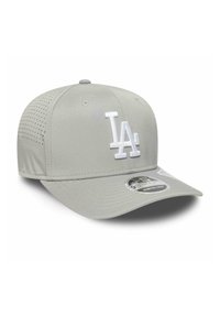 Gorra gris con visera curvada, fabricada en un tejido suave. Presenta un logo "LA" bordado en blanco y paneles laterales perforados para ventilación.