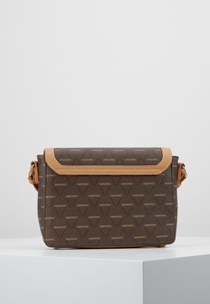 Sac bandoulière marron Valentino avec bordure beige et motif de logo répété, posé sur un socle blanc sur un fond uni.