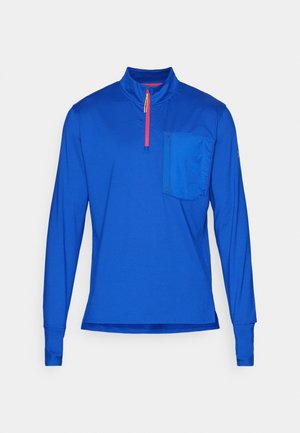 Langärmliges, halb-zip Oberteil aus leuchtend blauem Stoff. Mit einer Brusttasche und kontrastierendem roten Reißverschluss. Glatte Textur, sportlicher Schnitt.