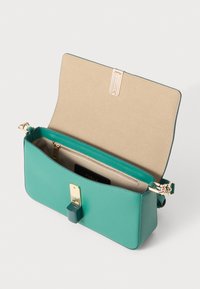 Teal leather handbag with a structured shape, gold hardware, and a beige interior. Features a clasp closure and a zip pocket inside.
