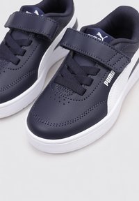 Sneaker di colore blu scuro con tomaia in pelle liscia, dettagli bianchi, una chiusura in velcro e lacci neri. Punta rotonda con fori per la traspirabilità.