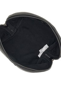 Interno di una borsa in pelle nera con finitura texturizzata. Presenta una chiusura a zip e rivestimento in tessuto. Contiene tasche laterali con zip e etichette.