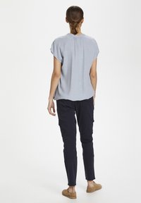 Ljusblå kortärmad topp med en avslappnad passform, tillsammans med mörkblå tapered cargobyxor med sidfickor och förstärkta sömmar.